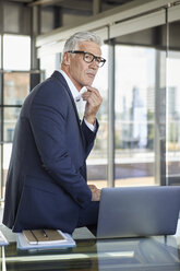 Successful manager sitting on desk, thinking - RBF06596