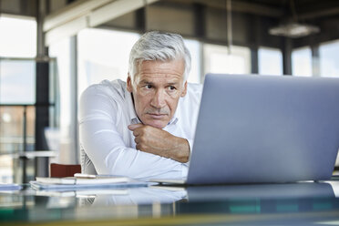 Businessman sitting at desk, trying to solve a problem - RBF06601
