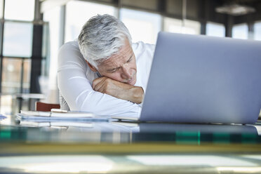 Exhausted businessman sleeping in front of laptop - RBF06602