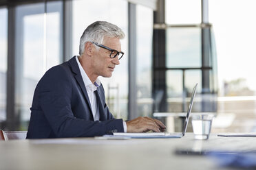 Geschäftsmann, der im Büro arbeitet und einen Laptop benutzt - RBF06607