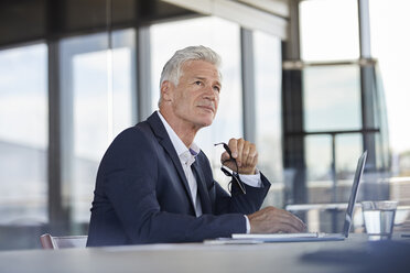 Businessman sitting in office, thinking - RBF06608