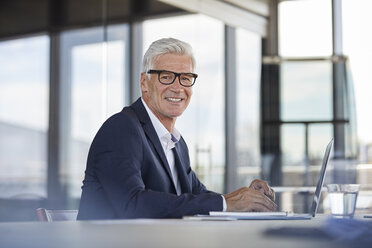 Businessman working in office, using laptop - RBF06609