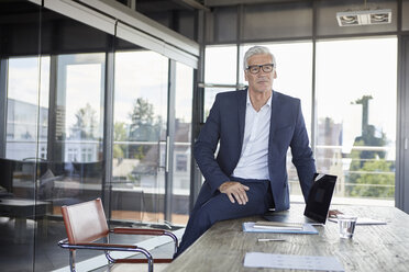 Successful manager sitting on desk, thinking - RBF06610