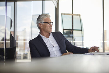 Businessman sitting in office, thinking - RBF06613