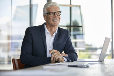 Businessman working in office, using laptop - RBF06618