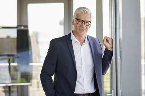 Portrait of a successful businessman, standing by window stock photo