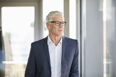 Worried businessman standing by window, thinking - RBF06667