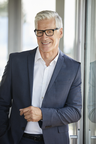 Portrait of a successful businessman, standing by window stock photo