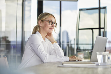 Businesswoman sitting at desk, thinking - RBF06703