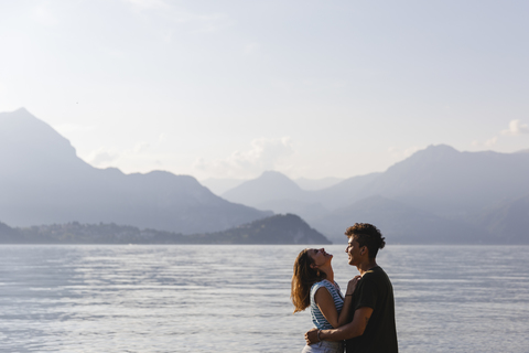 Glückliches, zärtliches junges Paar am Seeufer, lizenzfreies Stockfoto