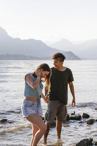 Glückliches junges Paar Hand in Hand am Seeufer, lizenzfreies Stockfoto