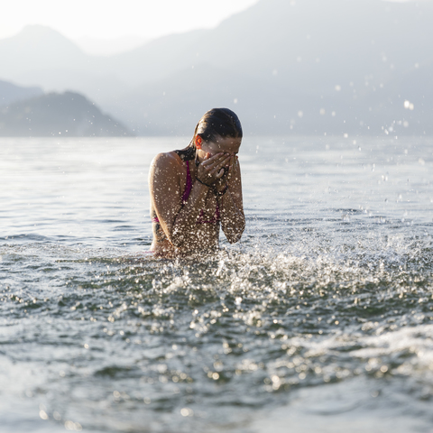 Junge Frau in einem See reibt sich die Augen, lizenzfreies Stockfoto