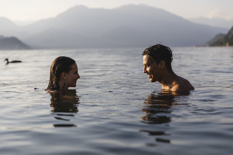 Glückliches junges Paar in einem See, das sich gegenseitig anlächelt, lizenzfreies Stockfoto