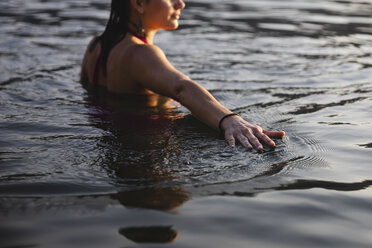 Die Hand einer jungen Frau berührt die Wasseroberfläche eines Sees - MRAF00304