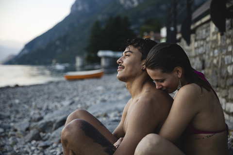 Zärtliches junges Paar entspannt sich nach einem Bad in einem See, lizenzfreies Stockfoto