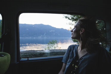 Junge Frau sitzt auf der Rückbank eines Autos und schaut aus dem Fenster - MRAF00318