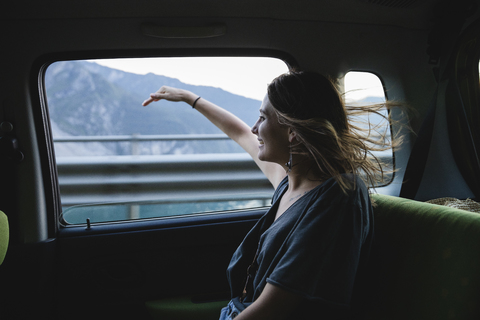 Happy young woman sitting on backseat in a car looking out of window stock photo