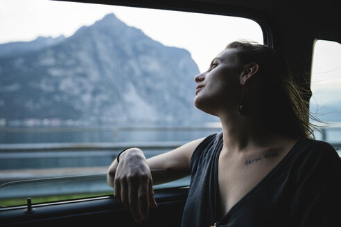 Young woman sitting on backseat in a car looking out of window - MRAF00323