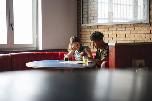 Junges Paar sitzt am Tisch in einem Café mit Karte - MRAF00329