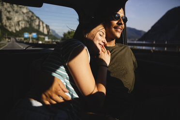 Smiling affectionate young couple sitting on backseat in a car - MRAF00334