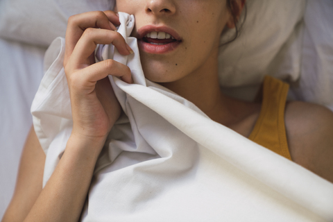 Offener Mund einer im Bett liegenden jungen Frau, lizenzfreies Stockfoto