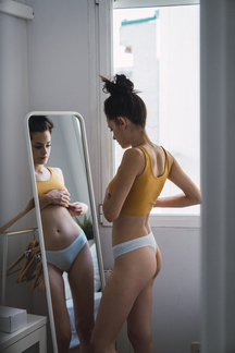 Young woman in underwear at home reflected in mirror - a Royalty