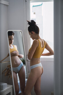 Young woman in underwear at home looking in mirror - KKAF01824