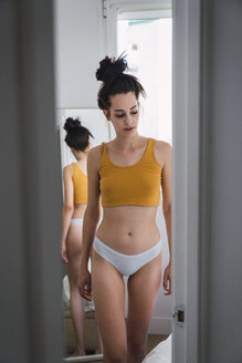 Junge Frau in Unterwäsche zu Hause reflektiert im Spiegel - KKAF01826