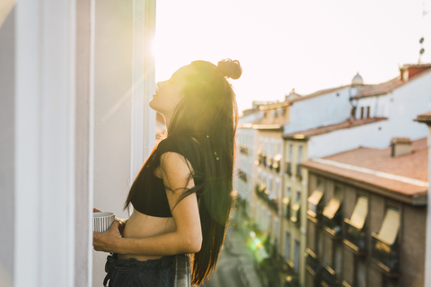 Beautiful young woman on balcony above the city at sunset stock photo