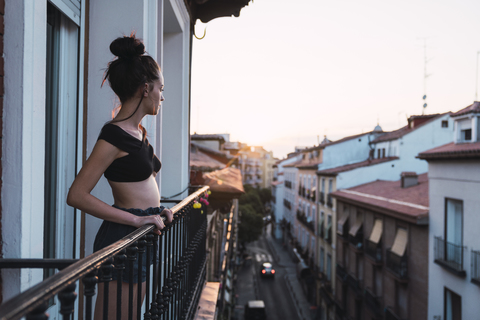 Schöne junge Frau auf Balkon über der Stadt bei Sonnenuntergang, lizenzfreies Stockfoto