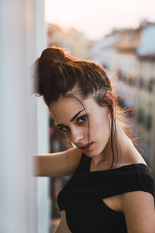 Portrait of beautiful young woman on balcony above the city at sunset - KKAF01851