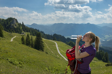 Deutschland, Bayern, Brauneck bei Lenggries, junge Frau in alpiner Landschaft, die Wasser aus einer Flasche trinkt - LBF02072