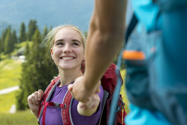 Deutschland, Bayern, Brauneck bei Lenggries, glückliche junge Frau wandert in alpiner Landschaft und hält die Hand ihres Freundes - LBF02075