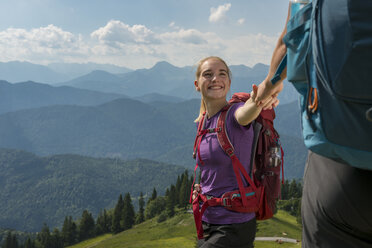 Deutschland, Bayern, Brauneck bei Lenggries, glückliche junge Frau wandert in alpiner Landschaft und hält die Hand ihres Freundes - LBF02077