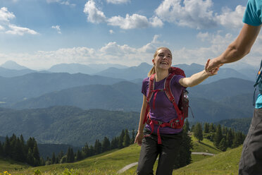 Deutschland, Bayern, Brauneck bei Lenggries, glückliche junge Frau wandert in alpiner Landschaft und hält die Hand ihres Freundes - LBF02079