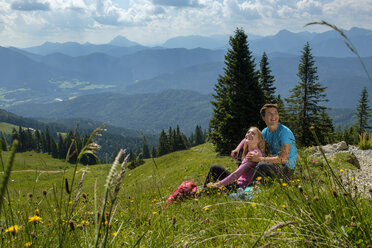 Germany, Bavaria, Brauneck near Lenggries, happy young couple having a break sitting in meadow in alpine landscape - LBF02087
