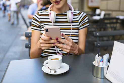 Junge Frau benutzt Smartphone in einem Straßencafé, Teilansicht - MGIF00245