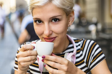 Porträt einer lächelnden jungen Frau, die in einem Straßencafé Espresso trinkt - MGIF00246