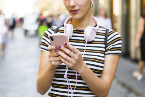 Frau mit Smartphone auf der Straße, Teilansicht, lizenzfreies Stockfoto