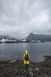 Norwegen, Lofoten, Rückansicht eines an der Küste stehenden Mannes - KKAF01859