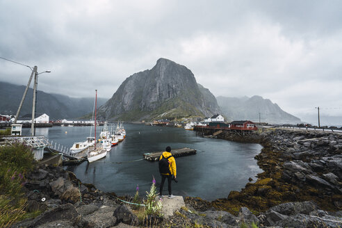 Norwegen, Lofoten, Rückansicht eines an der Küste stehenden Mannes - KKAF01863