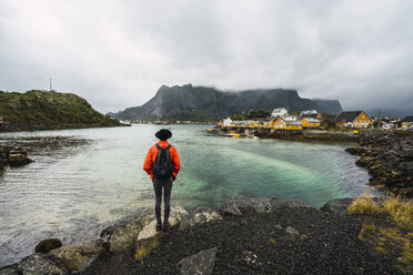 Norwegen, Lofoten, Rückansicht eines an der Küste stehenden Mannes - KKAF01867