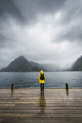 Norwegen, Lofoten, Rückansicht eines Mannes, der auf einer Mole an der Küste steht - KKAF01871