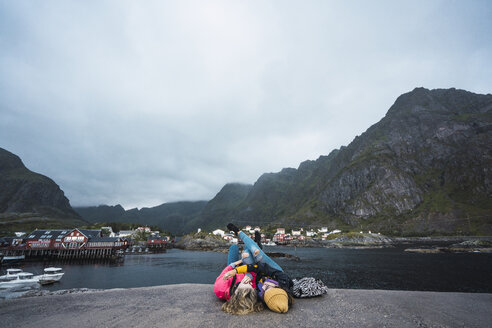 Norwegen, Lofoten, zwei junge Frauen liegen auf einem Pier an der Küste - KKAF01890