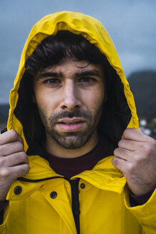 Norwegen, Lofoten, Porträt eines jungen Mannes in einer Regenjacke - KKAF01894