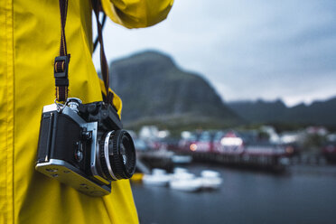 Norwegen, Lofoten, Nahaufnahme eines Mannes mit einer Kamera in einer Küstenstadt - KKAF01895