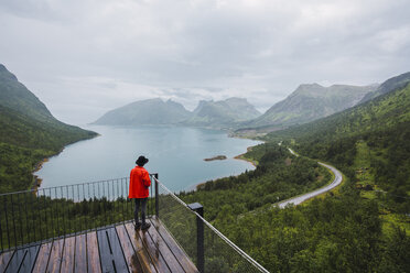 Norway, Senja island, rear view of man standing on an observation deck at the coast - KKAF01909