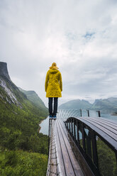 Norwegen, Insel Senja, Rückansicht eines Mannes, der auf einer Aussichtsplattform an der Küste steht - KKAF01910