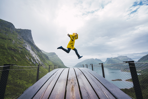 Norway, Senja island, man jumping on an observation deck at the coast stock photo