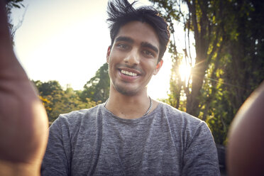 Portrait of a young man in a park at sunset, taking selfie - SRYF00794